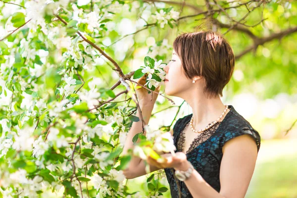 Porträtt av ung kvinna i den blomstrande trädgården på våren. Mandel blommor blommar. — Stockfoto