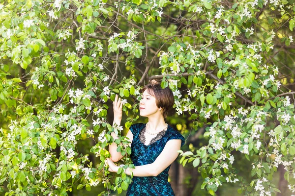 Porträtt av ung kvinna i den blomstrande trädgården på våren. Mandel blommor blommar. — Stockfoto