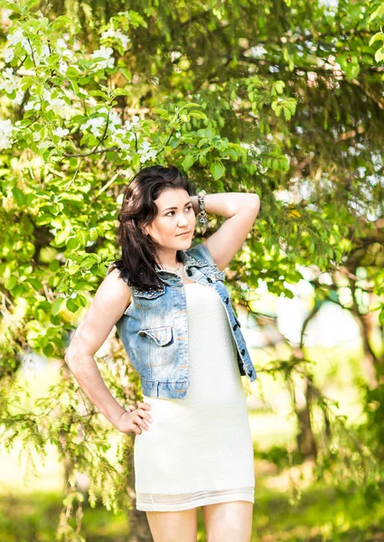 Femme de printemps en robe d'été marchant dans un parc verdoyant profitant du soleil. Ludique et belle fille de race mixte par une chaude journée ensoleillée — Photo