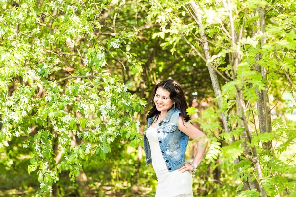 Femme de printemps en robe d'été marchant dans un parc verdoyant profitant du soleil. Ludique et belle fille de race mixte par une chaude journée ensoleillée — Photo