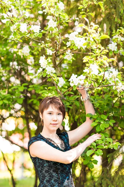 Beauté, personnes, concept d'été et de printemps - belle jeune femme sur fond de jardin fleuri vert — Photo