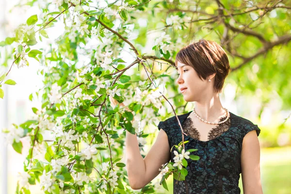 Våren flicka porträtt. Asiatisk kvinna ler glad på solig sommar eller vårdag utanför i blommande träd trädgård. Ganska blandad ras kaukasiska eller kinesiska asiatisk ung kvinna utomhus. — Stockfoto