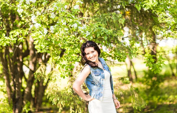 Femme de printemps en robe d'été marchant dans un parc verdoyant profitant du soleil. Ludique et belle fille de race mixte par une chaude journée ensoleillée — Photo