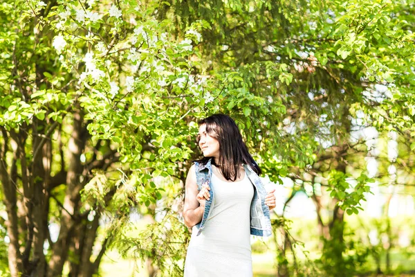 Lente vrouw in de zomer jurk wandelen in groen park genieten van de zon. Speels en mooi gemengd ras meisje op warme zonnige dag — Stockfoto