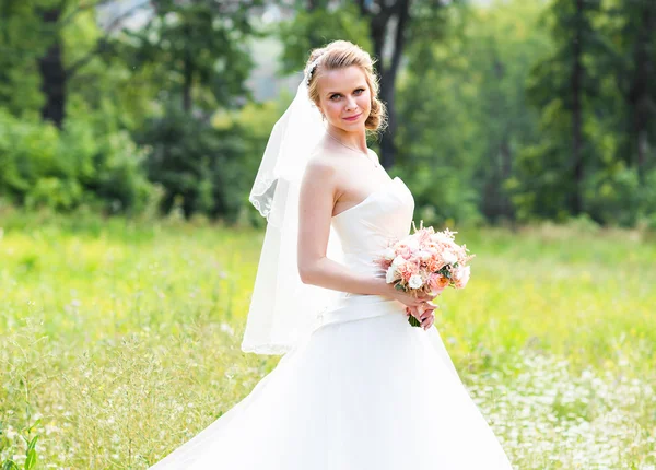 Mooie bruid met bruiloft boeket van bloemen buitenshuis in groen park. — Stockfoto