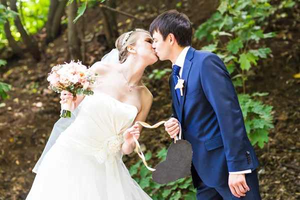 Braut und Bräutigam mit einem herzförmigen Schild. — Stockfoto