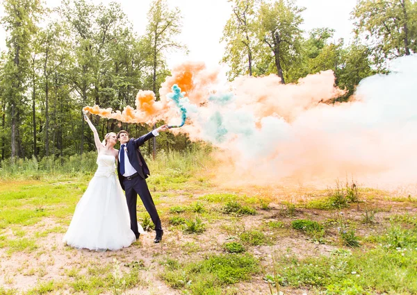 Wedding couple with color smoke in the summer park. — Stock Photo, Image