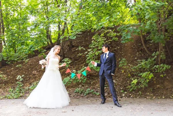 Νύφη και το γαμπρό στο πάρκο. Διακοσμήσεις γιρλαντών — Φωτογραφία Αρχείου