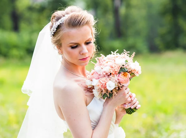 Schöne Braut mit Hochzeitsstrauß von Blumen im Freien im grünen Park. — Stockfoto