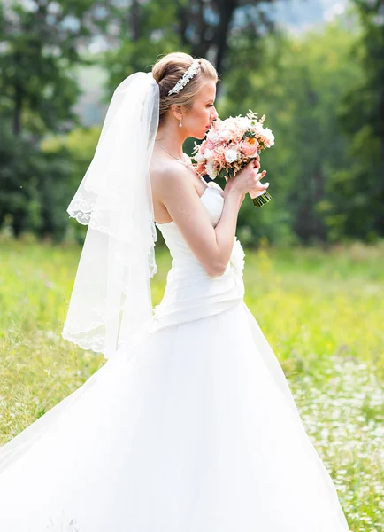 Schöne Braut mit Hochzeitsstrauß von Blumen im Freien im grünen Park. — Stockfoto