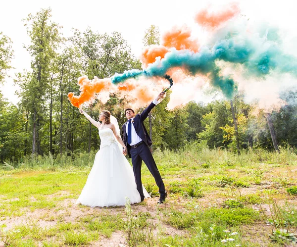 Весільна пара з кольоровим димом в літньому парку . — стокове фото