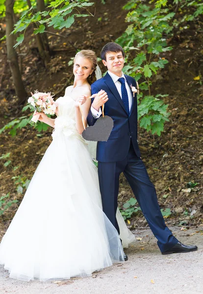 Bruden och brudgummen har en skylt med hjärtformade. — Stockfoto