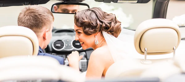 Mooie jonge paar bruid en bruidegom poseren in cabriolet — Stockfoto