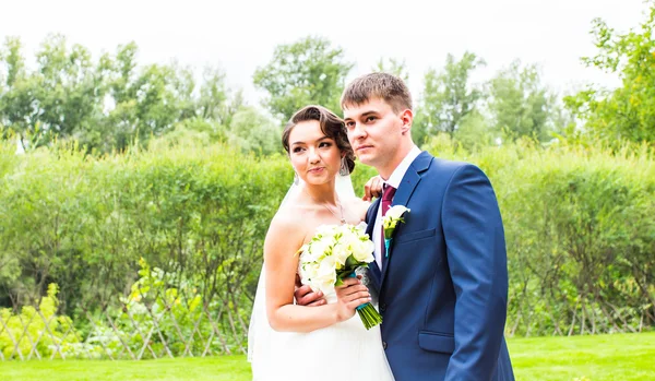 Novia y novio en un parque. vestido de novia. Ramo de flores de boda nupcial — Foto de Stock