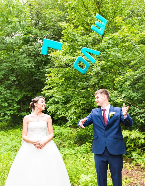 Happy bride and groom holding LOVE letters — Stock Photo, Image