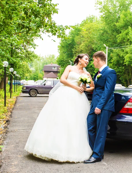 Belle jeune mariée couple et marié posant avec cabriolet — Photo