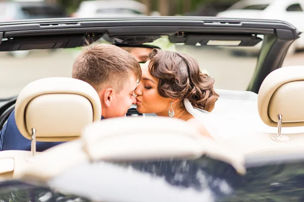 Casal jovem bonita noiva e noivo posando em cabriolet — Fotografia de Stock