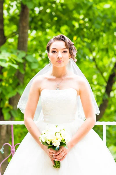 Bella sposa ragazza in abito da sposa con mazzo di fiori, ritratto all'aperto — Foto Stock