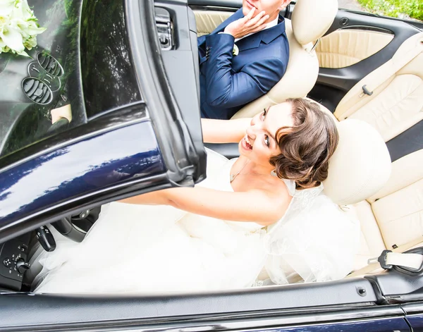 Casal jovem bonita noiva e noivo posando em cabriolet — Fotografia de Stock