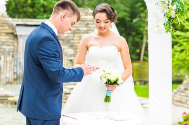 damat ve gelin bir yüzük parmağında düğün töreni giyiyor. Altın, sembol, din, aşk.