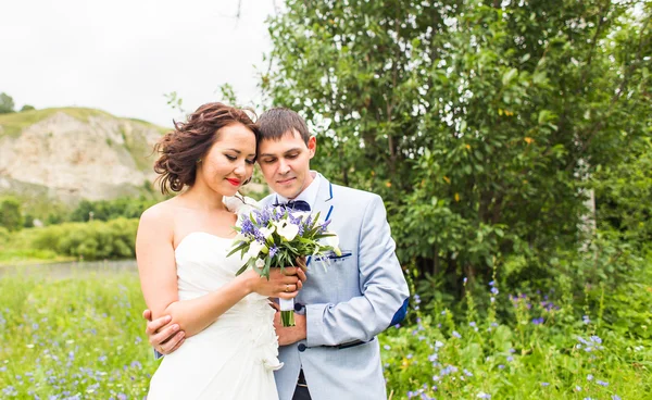 Novia y novio en la boda Día caminando al aire libre en la naturaleza de primavera. Feliz Recién casados abrazándose en el parque verde . — Foto de Stock