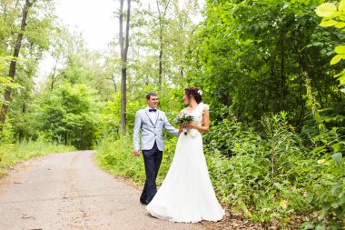 Gelin ve damat gün açık havada yürüyüş düğününde Doğa bahar. Yeşil park kucaklayan mutlu yeni evli.