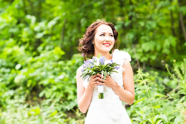 Sposa che tiene bouquet di gigli di calla bianchi e fiori blu — Foto Stock