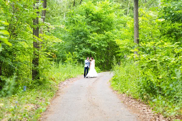 Panny młodej i pana młodego na wesela na zewnątrz chodzenie na wiosnę natura. Szczęśliwy Newlywed ogarniecie w parku. — Zdjęcie stockowe