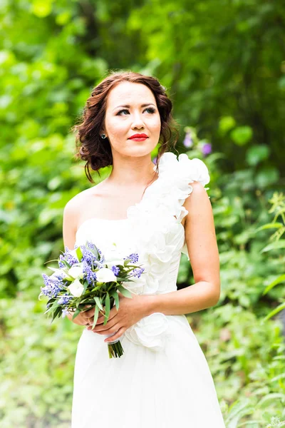Bride holding bouquet of white calla lilies and blue flowers