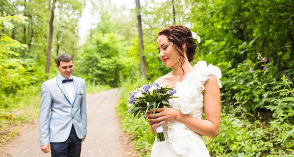 Bruid en bruidegom op de bruiloft dag buitenshuis lopen op lente natuur. Gelukkig Newlywed omarmen in groen park. — Stockfoto