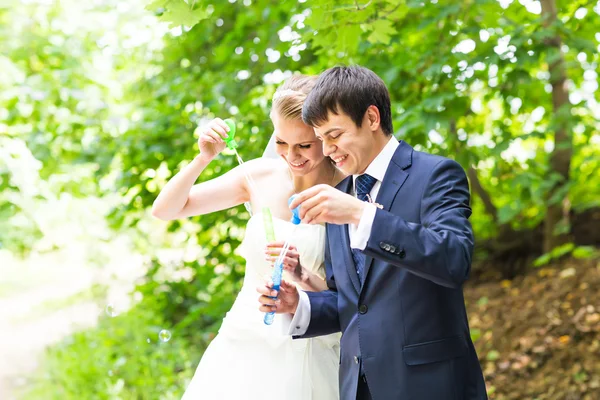 Hermosa boda pareja soplando burbujas — Foto de Stock