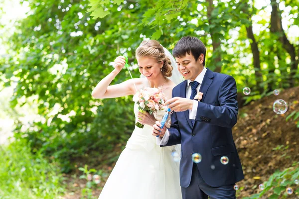 Beautiful wedding couple blowing bubbles — Stock Photo, Image