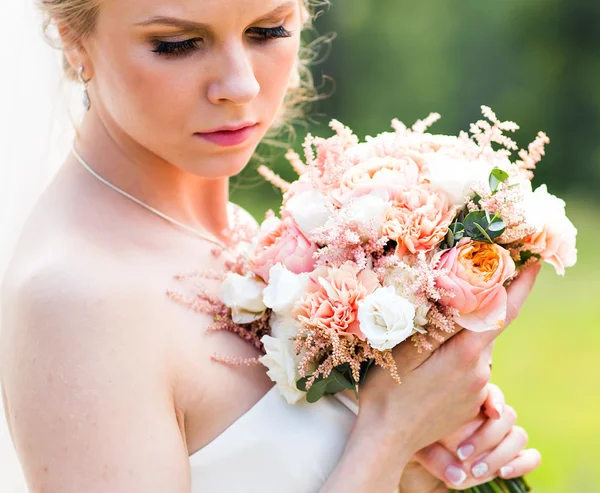 Mooie bruid met bruiloft boeket van bloemen buitenshuis in groen park. — Stockfoto