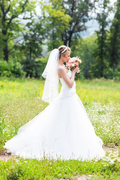 Mooie bruid met bruiloft boeket van bloemen buitenshuis in groen park. — Stockfoto