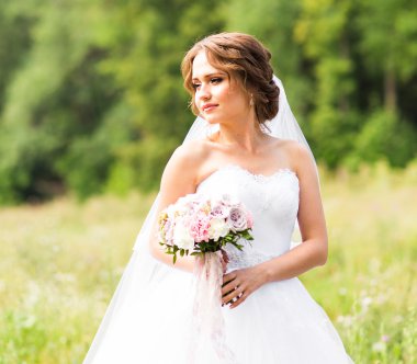 Güzel gelin kız gelinlik ve buket çiçek, açık havada dikey