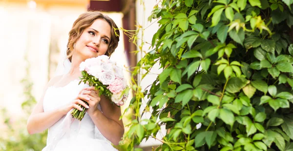 Bela noiva com buquê de flores ao ar livre — Fotografia de Stock