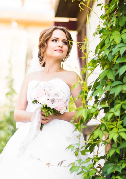 Menina noiva bonita em vestido de noiva e buquê de flores, ao ar livre retrato — Fotografia de Stock