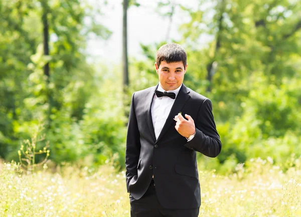 Retrato de novio elegante guapo en traje clásico negro al aire libre —  Fotos de Stock