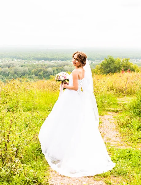 Menina noiva bonita em vestido de noiva e buquê de flores, ao ar livre retrato — Fotografia de Stock
