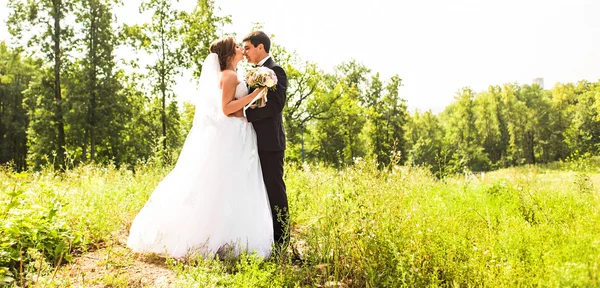 Νέοι γαμήλιο ζεύγος απολαμβάνοντας ρομαντικές στιγμές έξω σε ένα λιβάδι το καλοκαίρι — Φωτογραφία Αρχείου