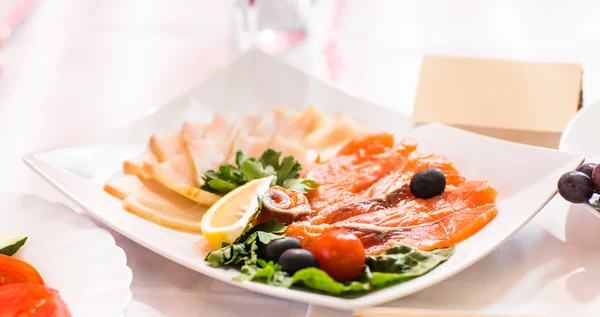 Catering-Platte mit geschnittenem gepökeltem Fleisch und Fisch mit Gemüsedekoration auf dem Ostertisch — Stockfoto