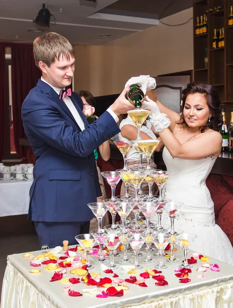 Наречений і наречений поливають шампанське в склянку. Піраміда шампанського . — стокове фото