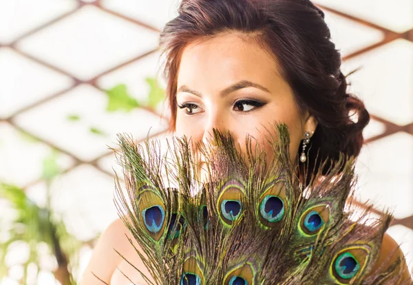 Mooie vrouw close-up met ventilator gemaakt van peacock feather — Stockfoto