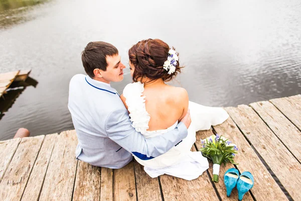 Schönes junges Hochzeitspaar sitzt auf der Seebrücke — Stockfoto