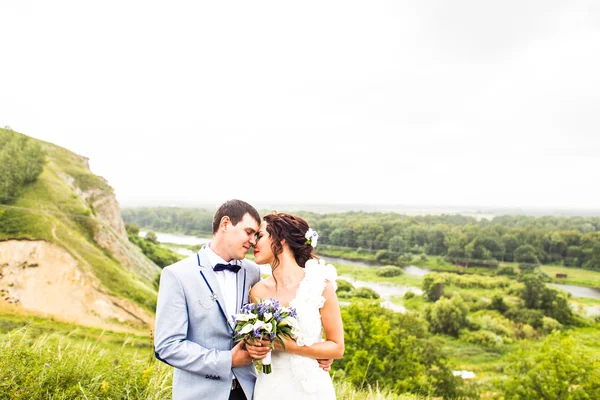 Bruid en bruidegom op de bruiloft dag buitenshuis lopen op lente natuur. Gelukkig Newlywed omarmen in groen park. — Stockfoto
