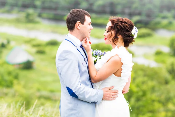 Noiva e noivo no dia do casamento andando ao ar livre na natureza de primavera. Feliz recém-casado abraçando no parque verde . — Fotografia de Stock