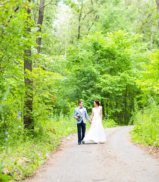 Невеста и жених на свадьбе День прогулки на свежем воздухе по весенней природе. Счастливая новобрачная обнимается в зеленом парке . — стоковое фото