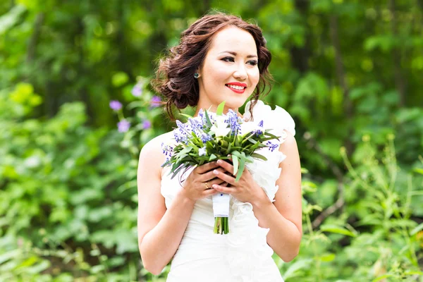 Nevěsta drží kytici bílých lilie calla a modré květy — Stock fotografie