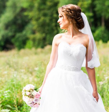 Güzel gelin kız gelinlik ve buket çiçek, açık havada dikey