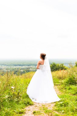 Güzel gelin kız gelinlik ve buket çiçek, açık havada dikey